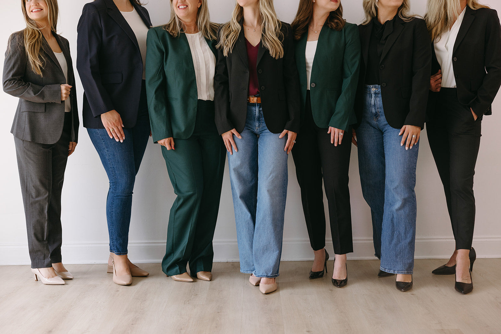 Group of women in business attire standing in a line against a plain background